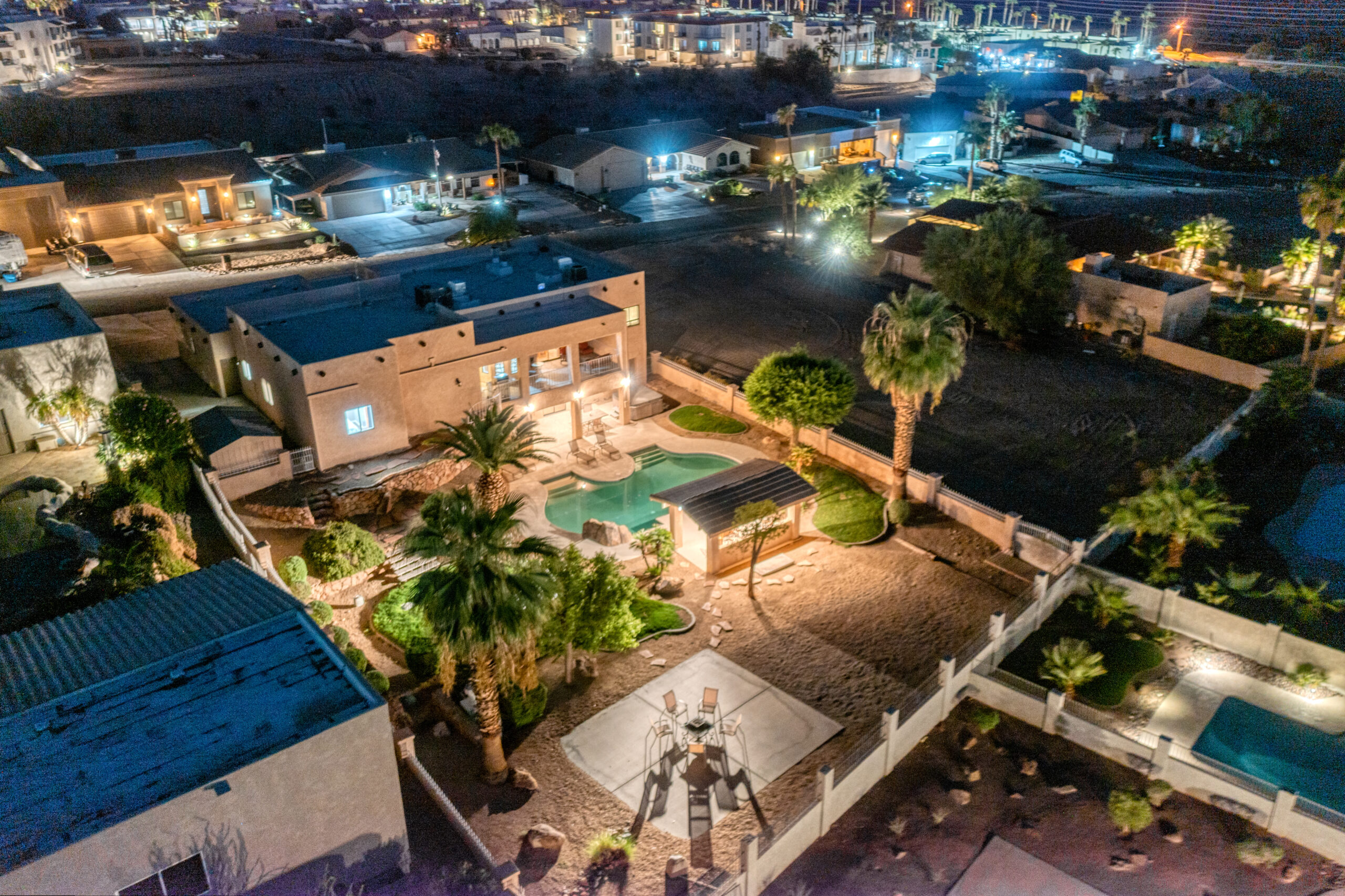 Backyard pool and patio illuminated at night captured by drone in Lake Havasu luxury home
