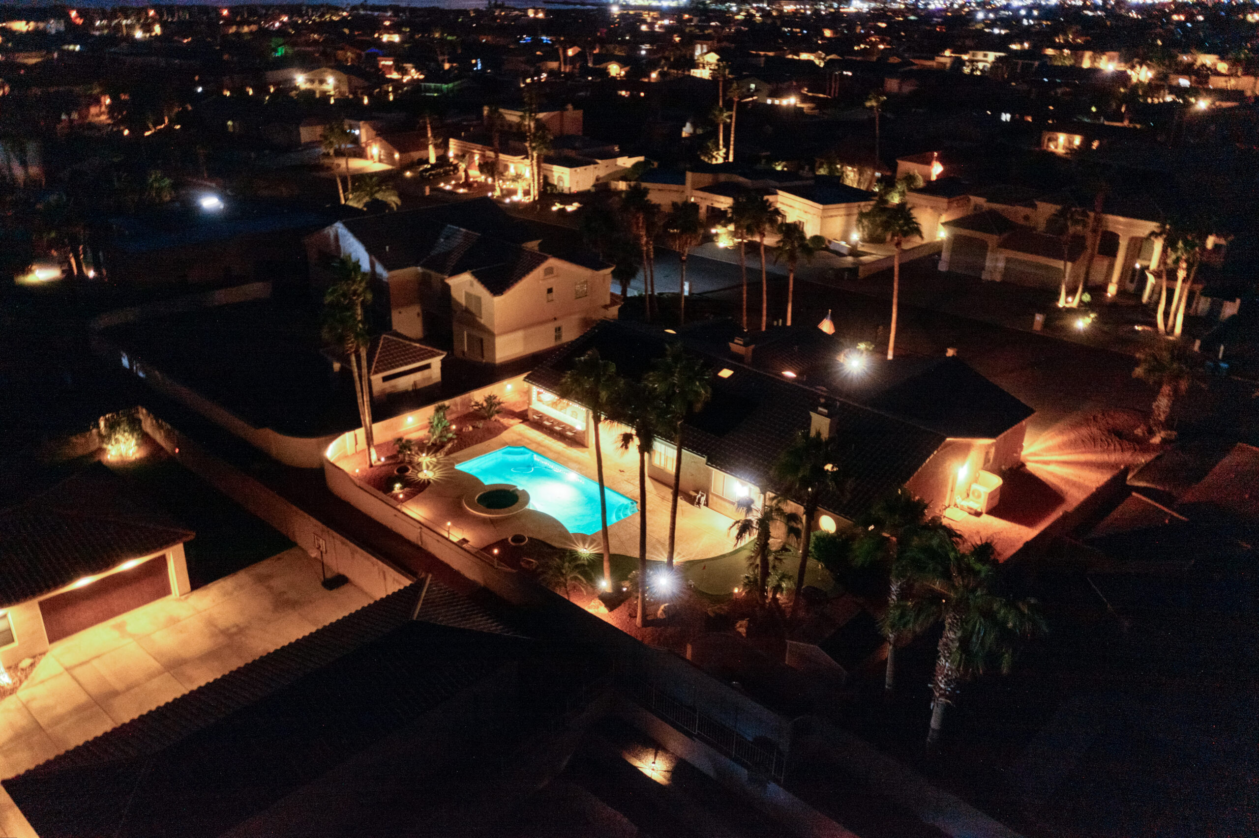 Backyard pool and patio with ambient lighting at night designed for entertaining in Lake Havasu luxury home