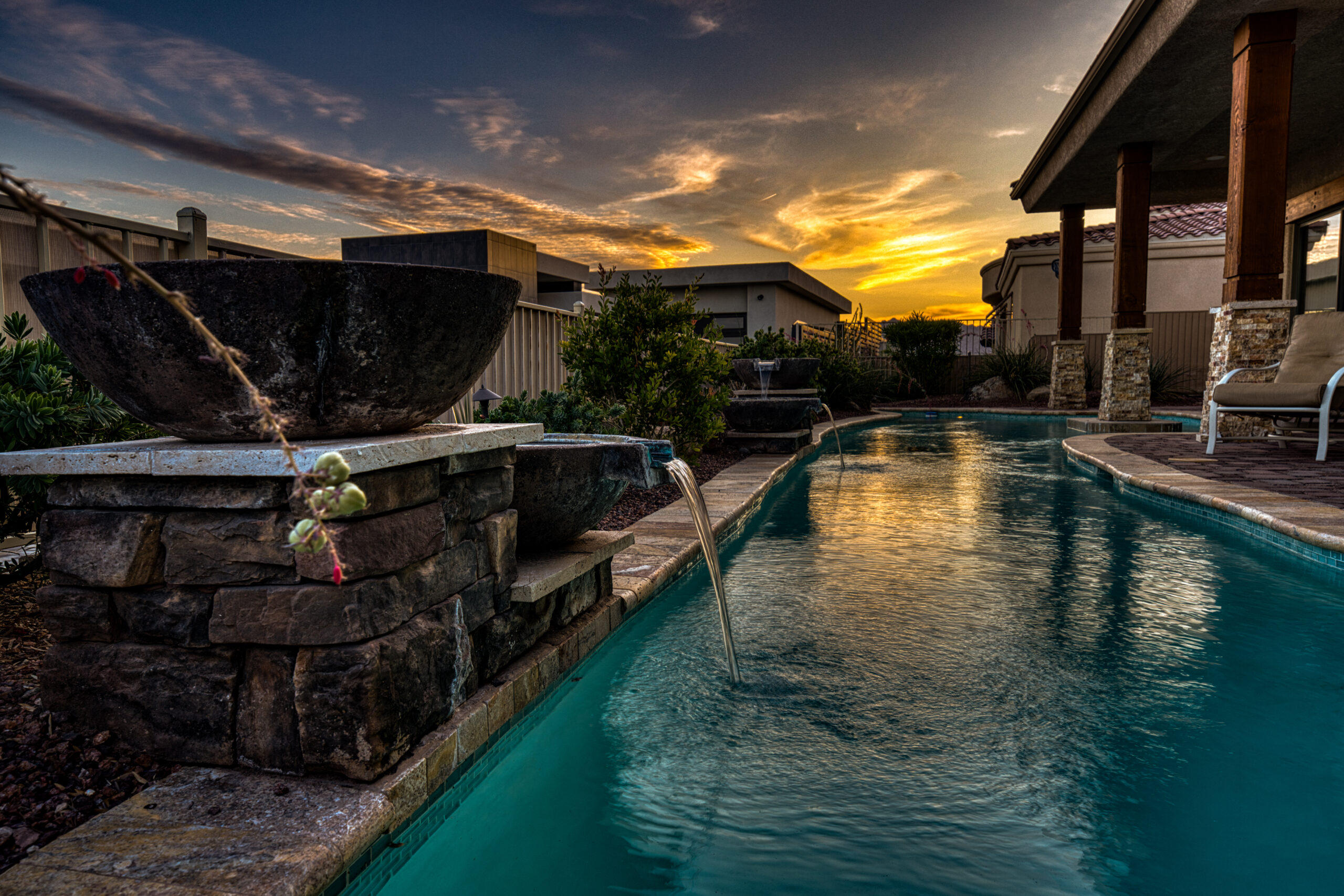 Backyard pool with stone waterfall feature at sunset in Lake Havasu luxury home
