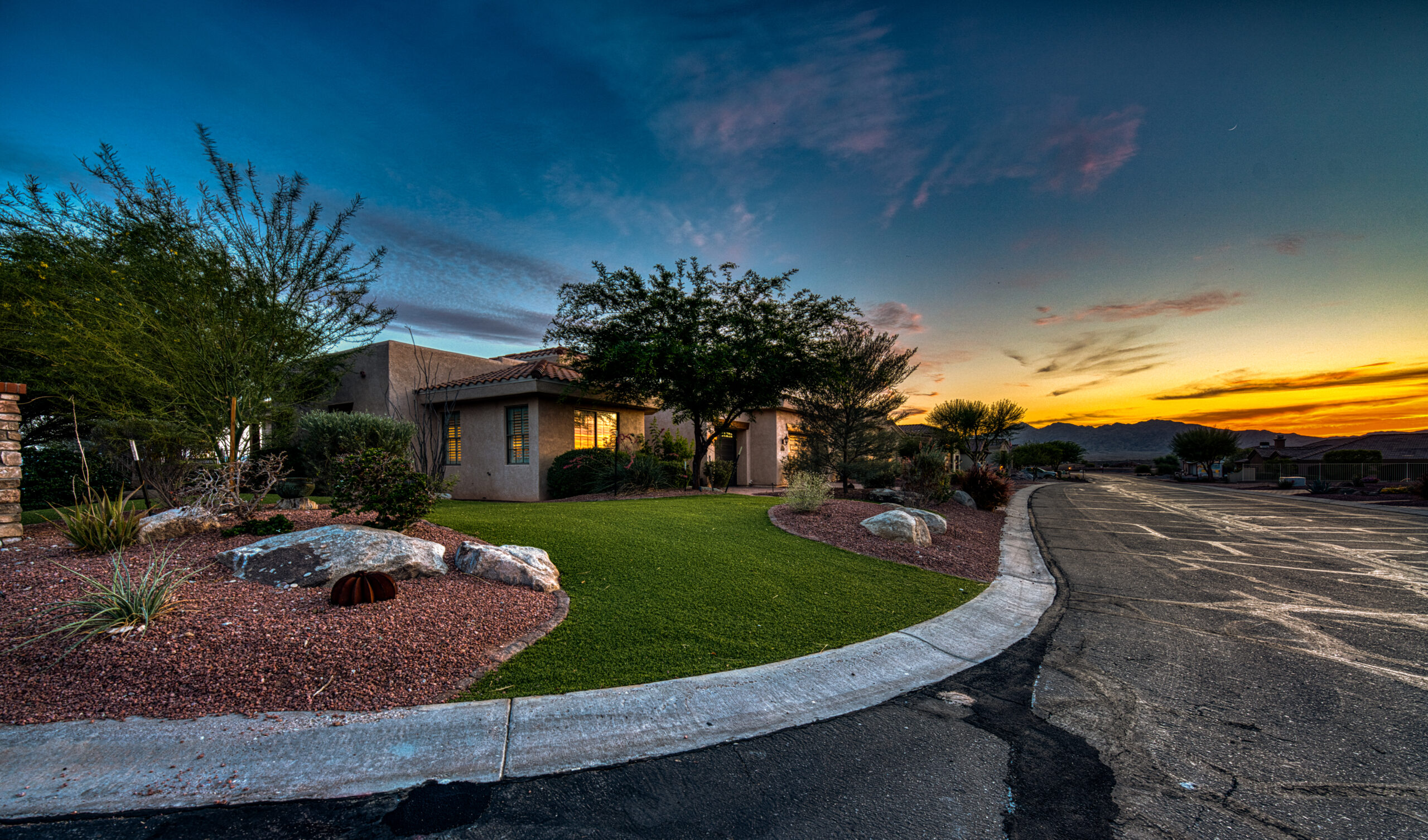 Corner lot home with curved street view and sunset sky in Lake Havasu neighborhood
