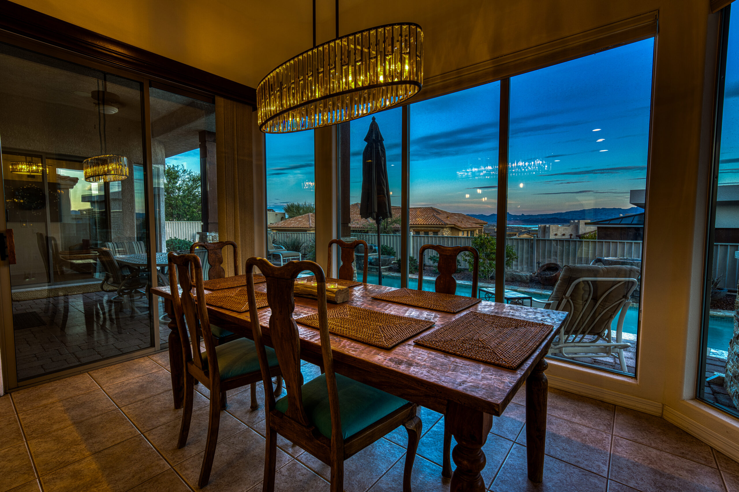 Dining room with large windows overlooking pool and sunset sky in Lake Havasu home