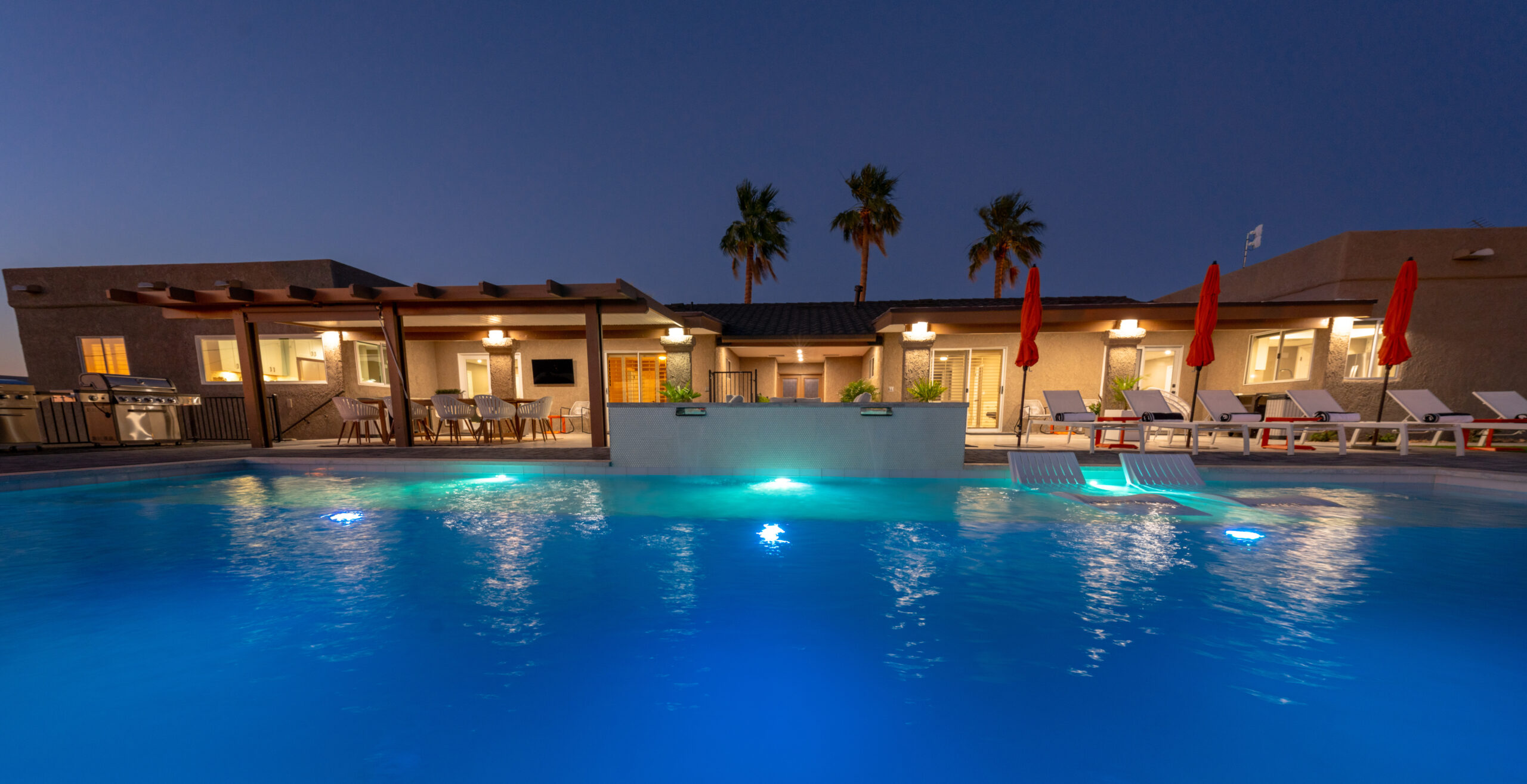 Luxury pool with lighting and outdoor seating area at night in Lake Havasu property