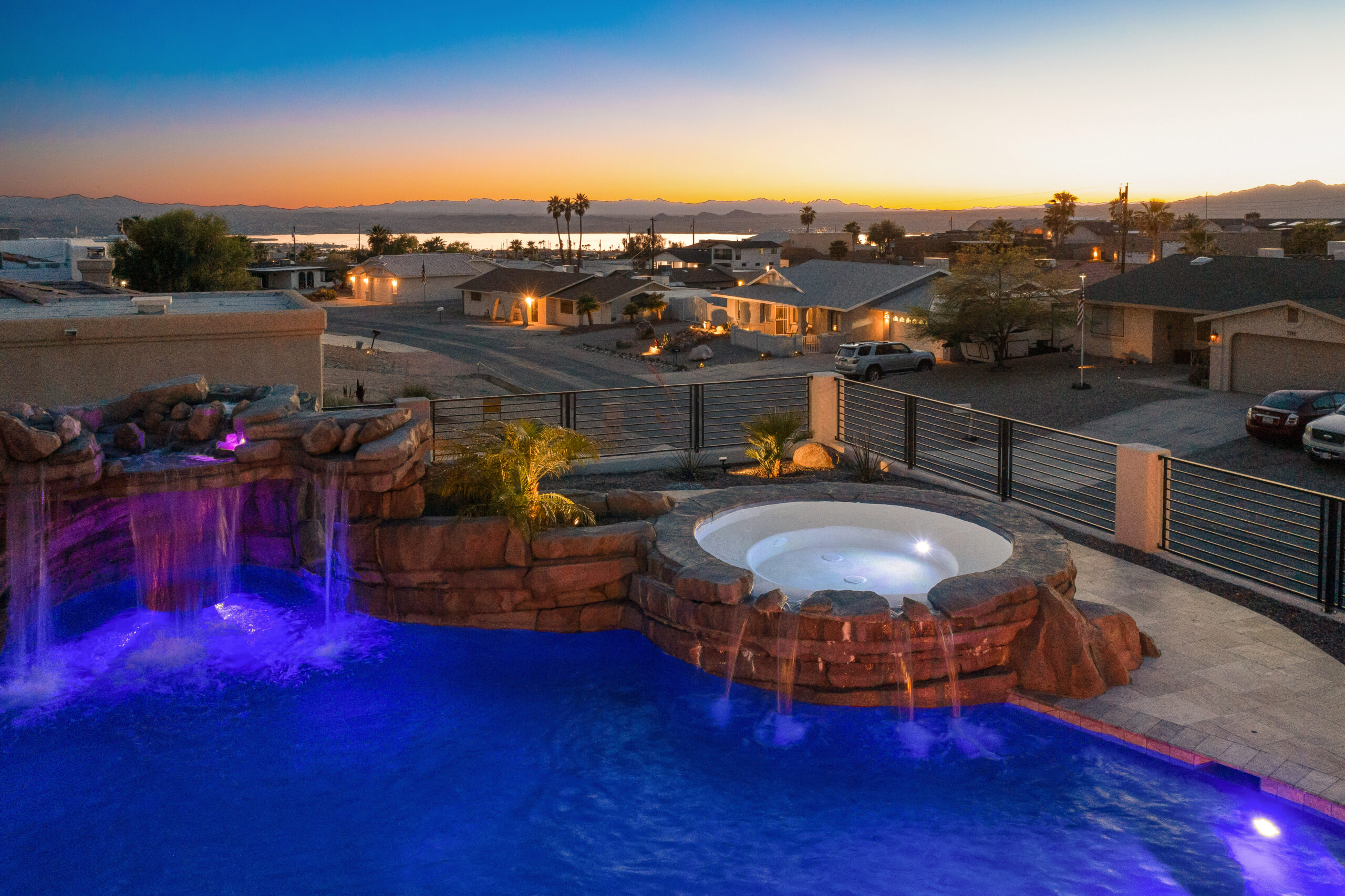 Luxury pool and spa with waterfall feature at sunset in Lake Havasu backyard