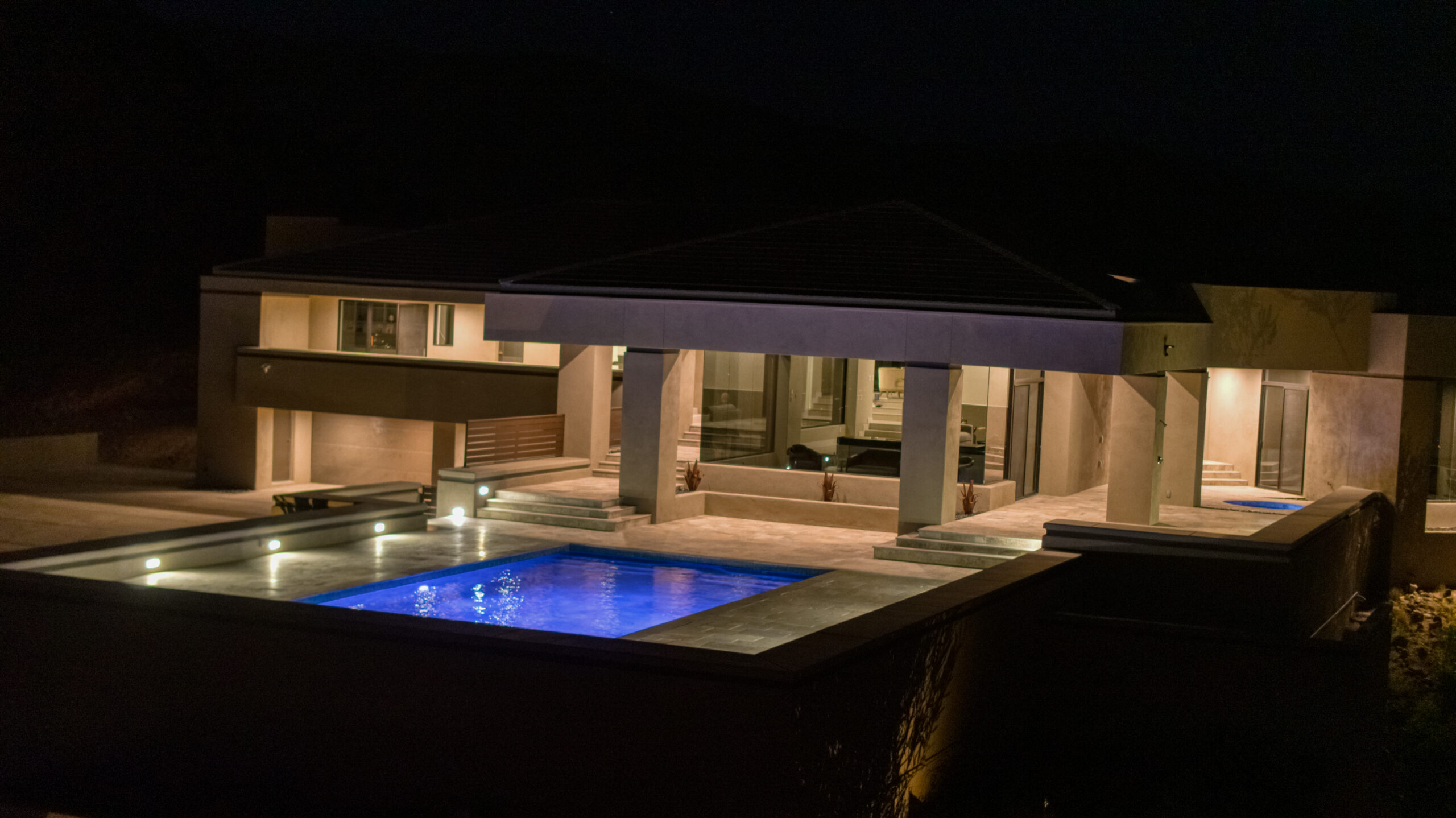 Aerial night view of modern Lake Havasu home with illuminated pool and clean architectural lines