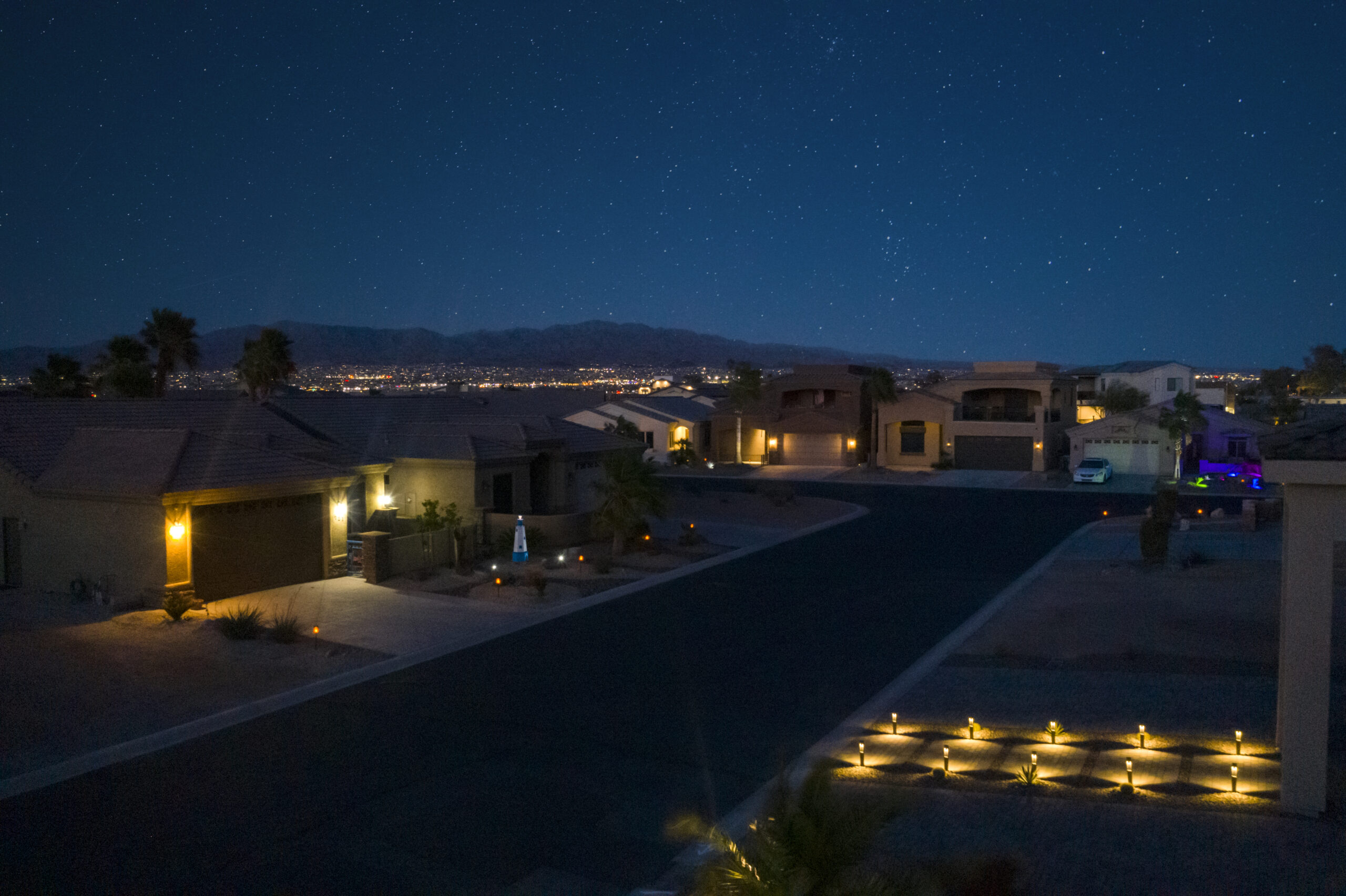 Residential neighborhood at night with city lights and mountain backdrop in Lake Havasu