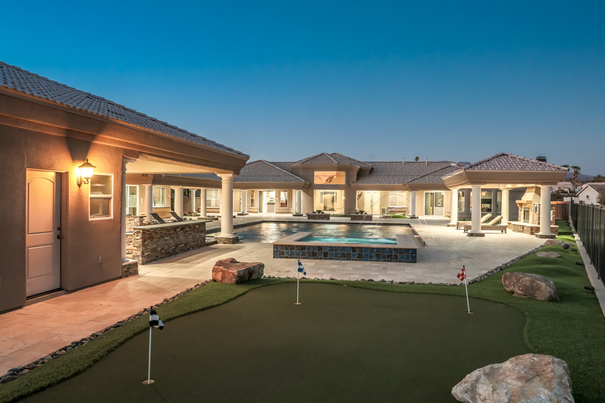 Large luxury estate courtyard with pool, spa, and putting green at twilight in Lake Havasu